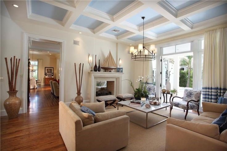 A stylish living room featuring a ceiling fan and coffered ceilings to elevate overall interior.